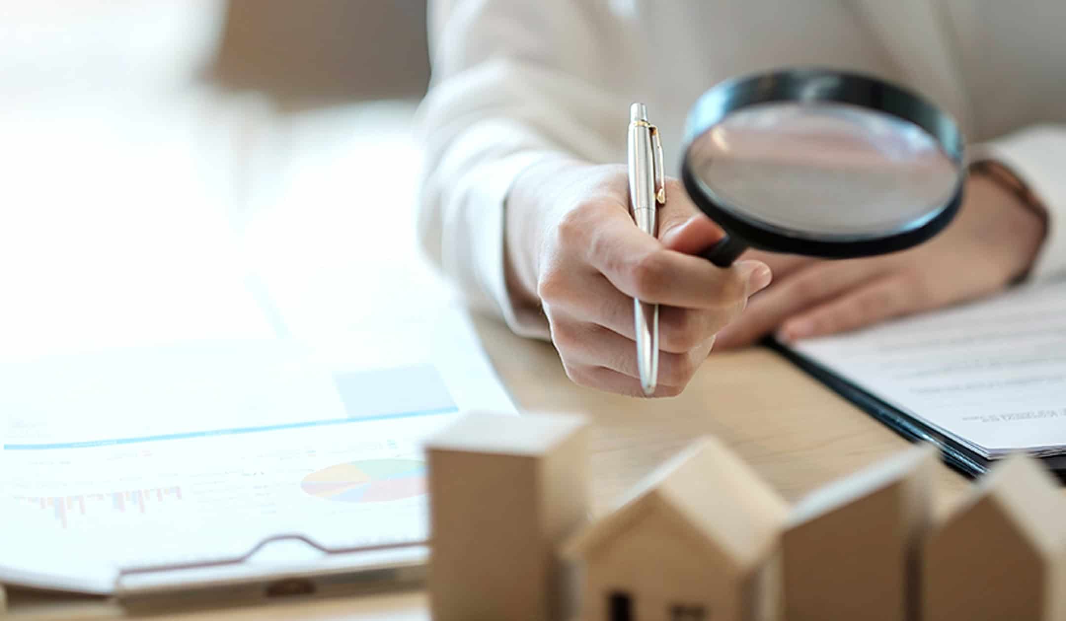 Magnifying glass examining property valuation documents for accurate appraisal.