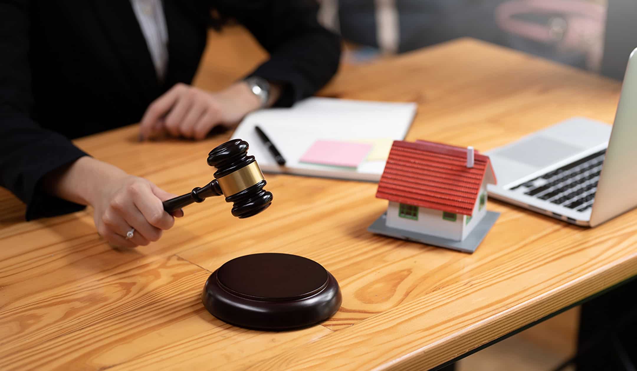 Business professional holding gavel during property appraisal discussion.