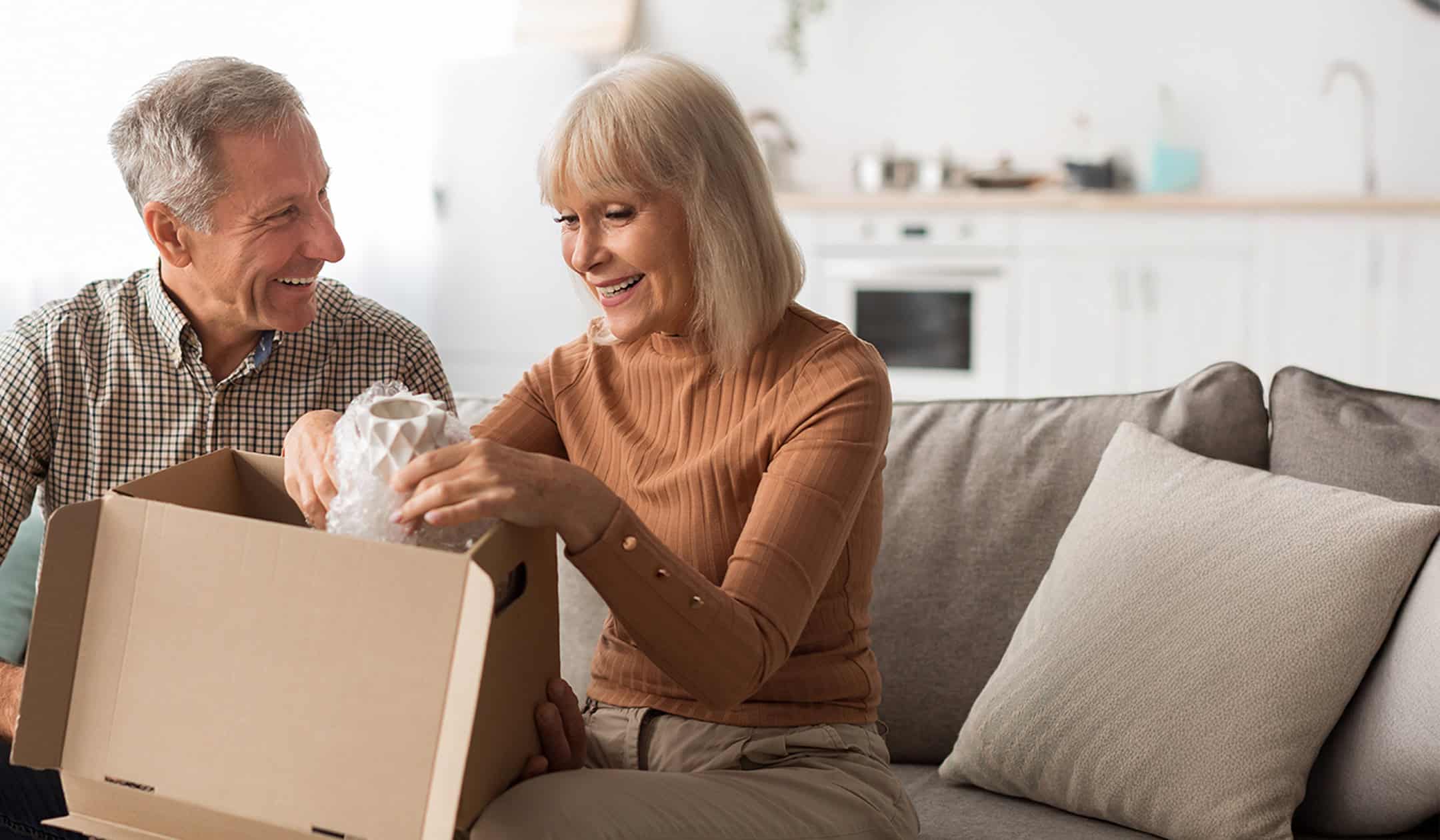 Happy senior couple opening a box with belongings in their new home.