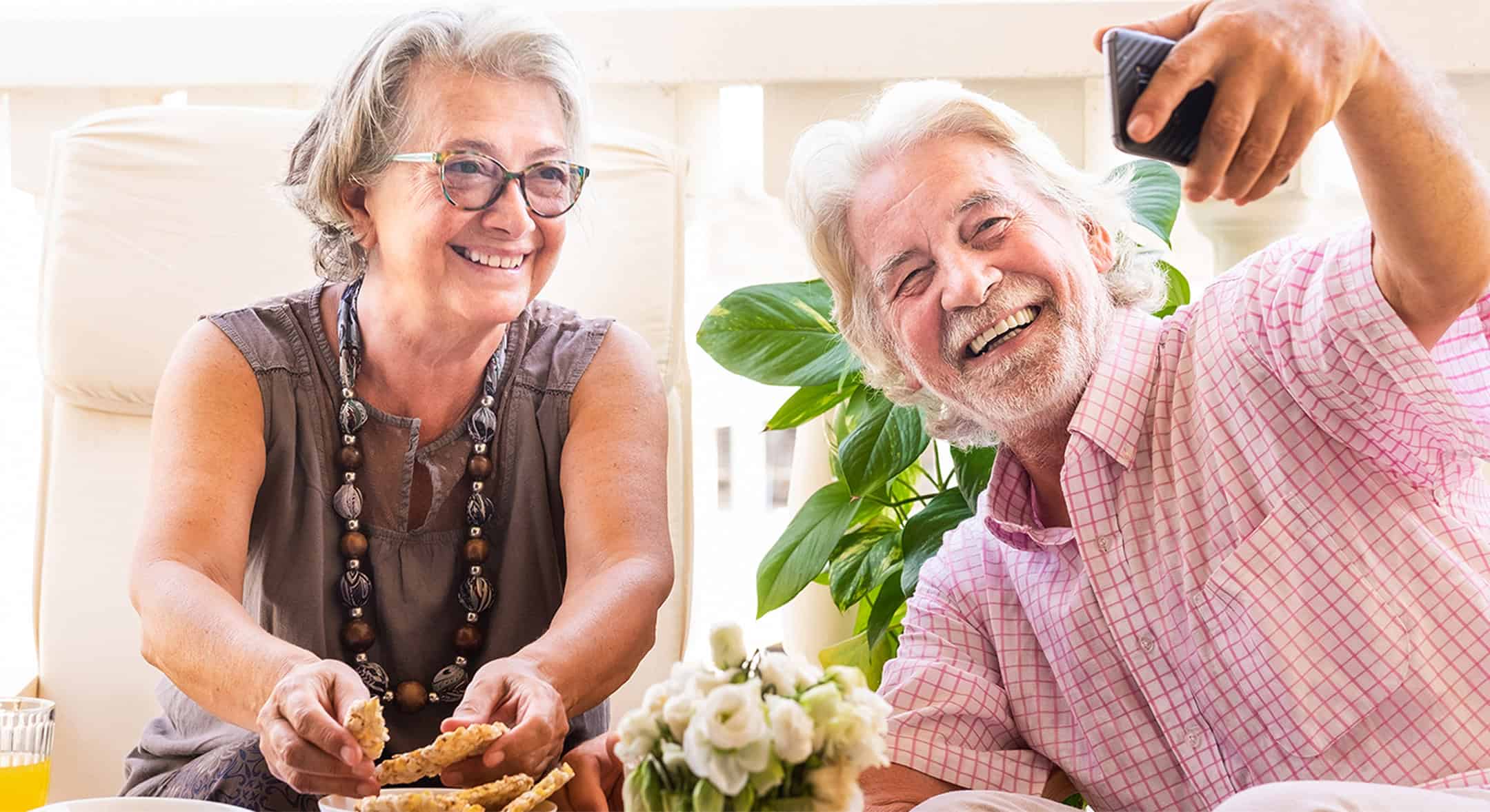 Happy elderly couple taking a selfie at Seava Nest senior care facility.