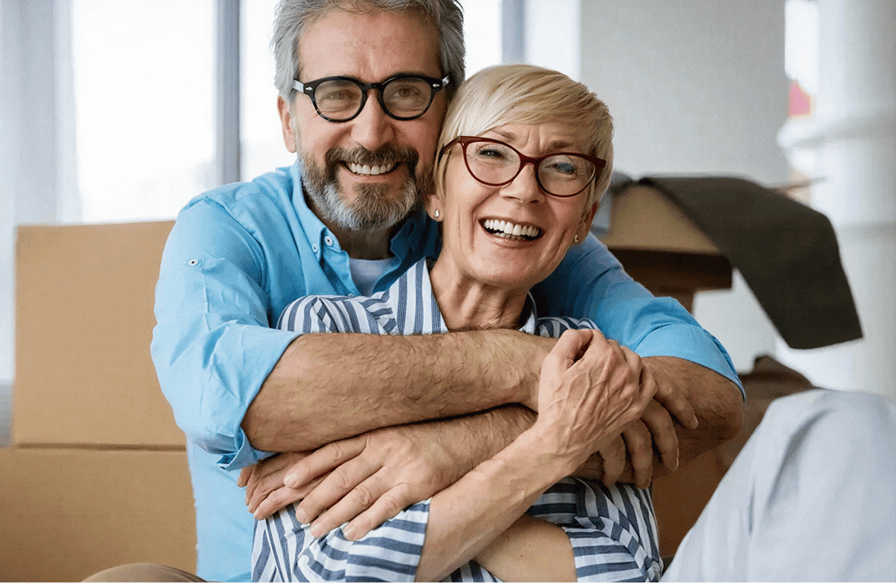 Elderly couple smiling and embracing in a cozy home setting, representing comfort and new beginnings.