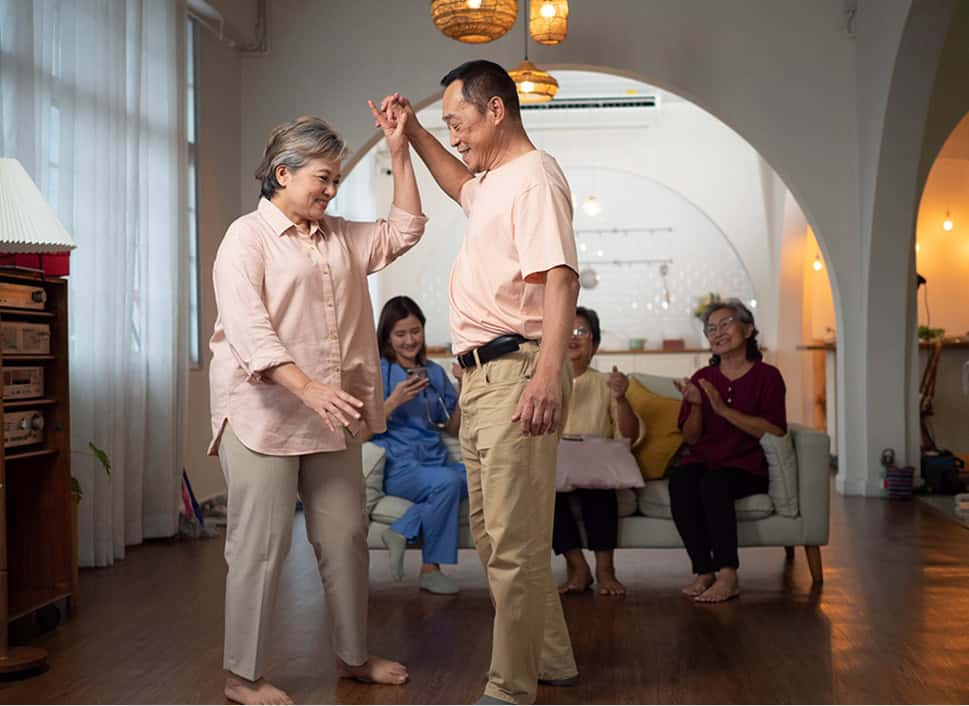 Senior dancing with family in cozy living room, enjoying quality time and creating joyful memories.