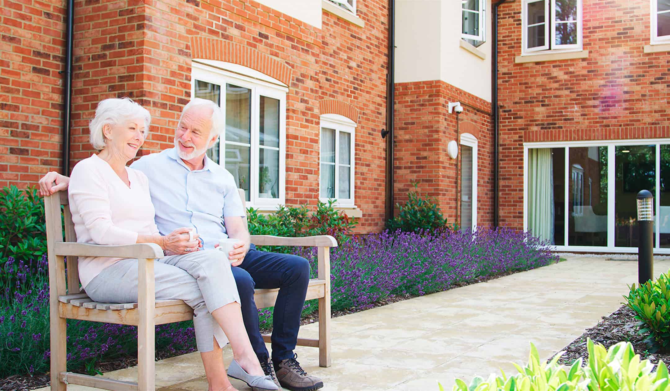 Senior couple relaxing on garden bench during home renovation.