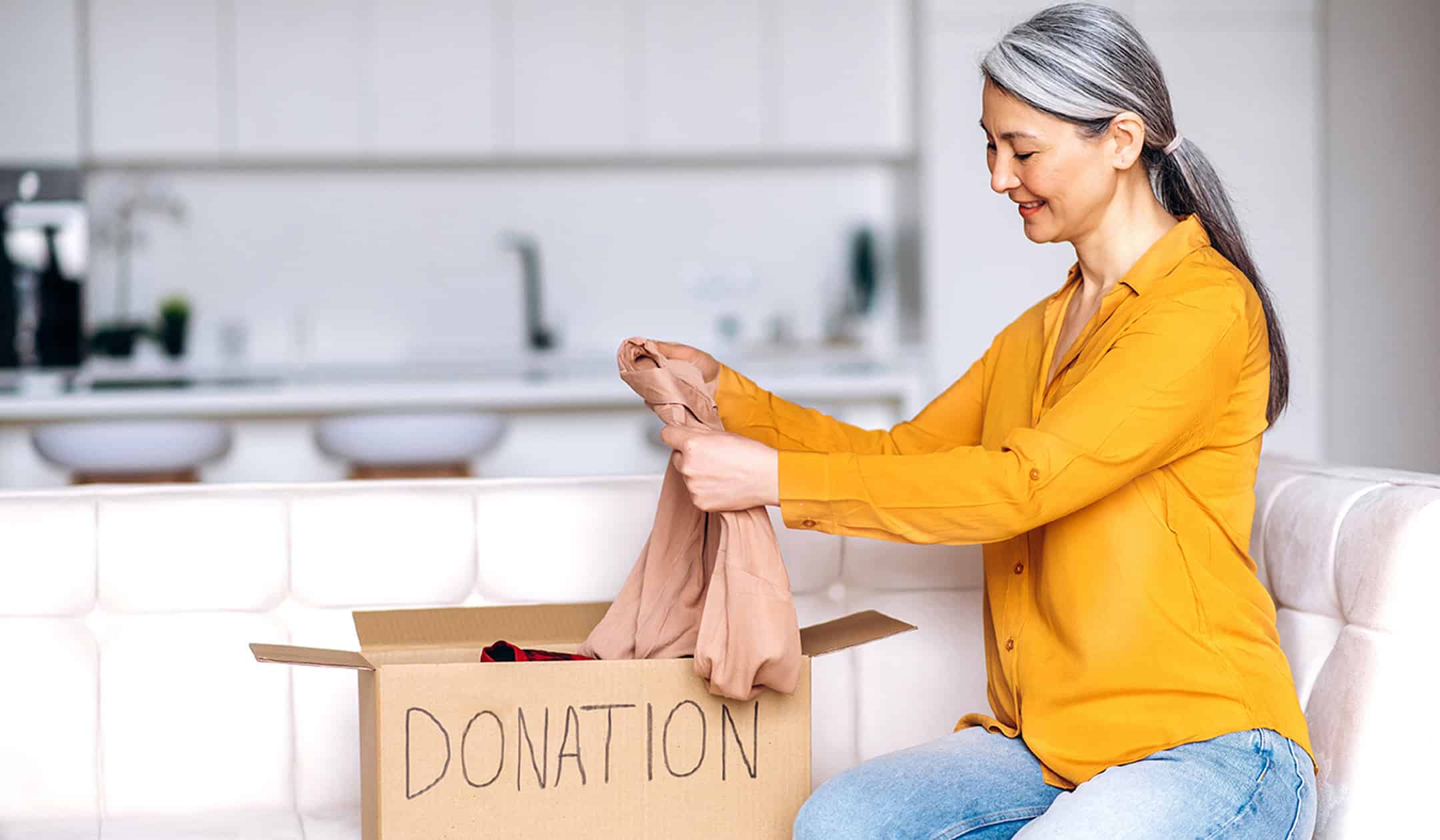 Woman packing clothes into donation box for finding new homes.