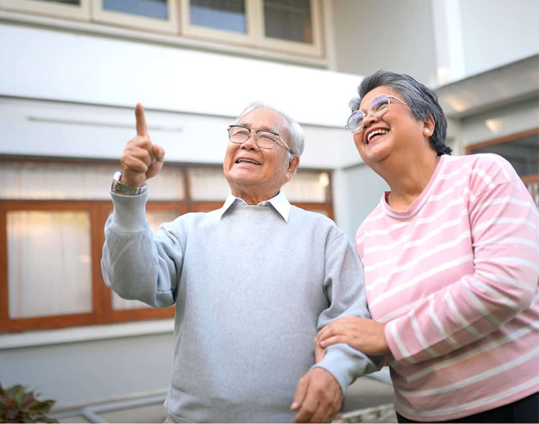 Elderly man and woman smiling and laughing outside, enjoying quality time together at Seava Nest.